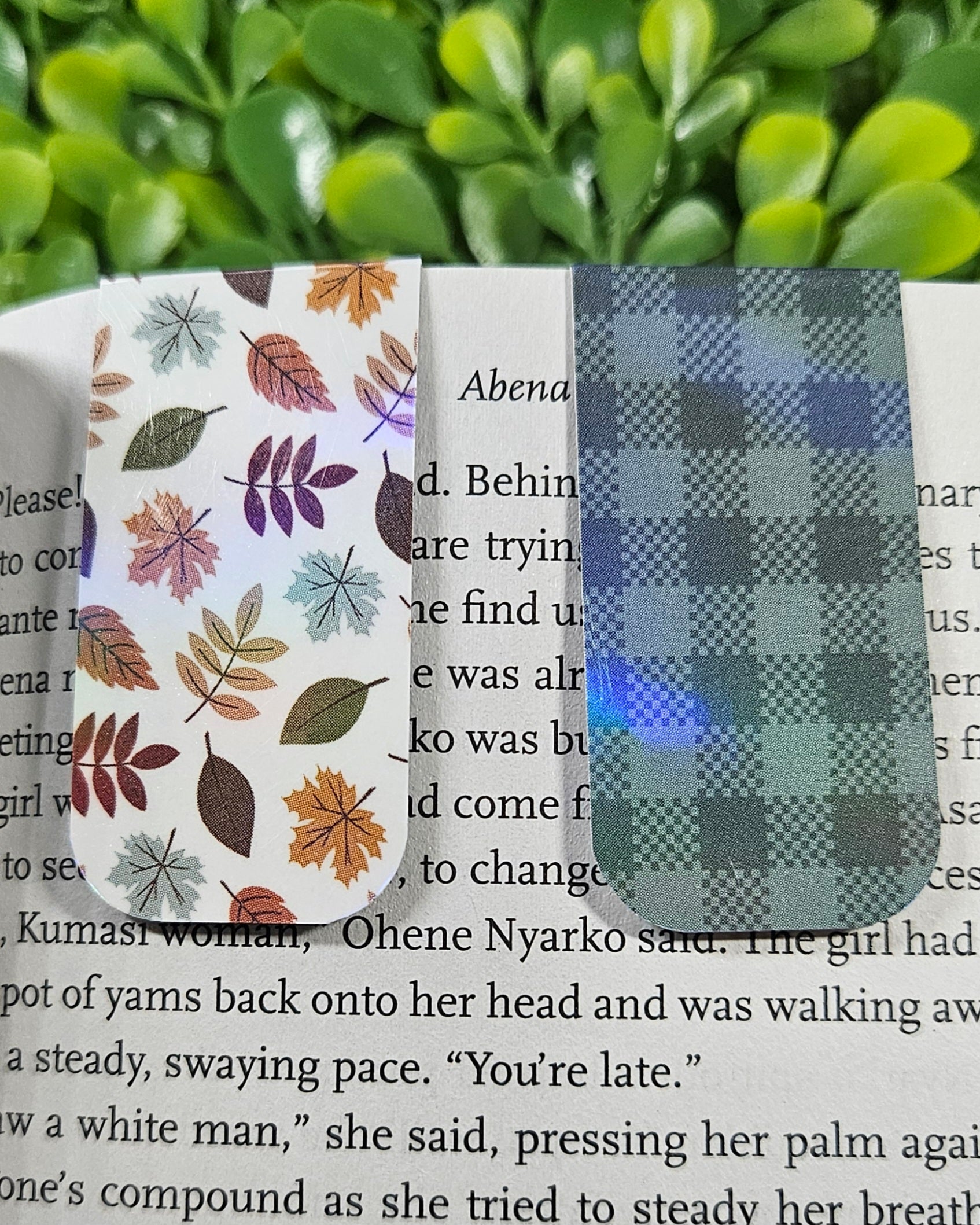 Handmade holographic magnetic bookmarks with a leafy and plaid designs on a book