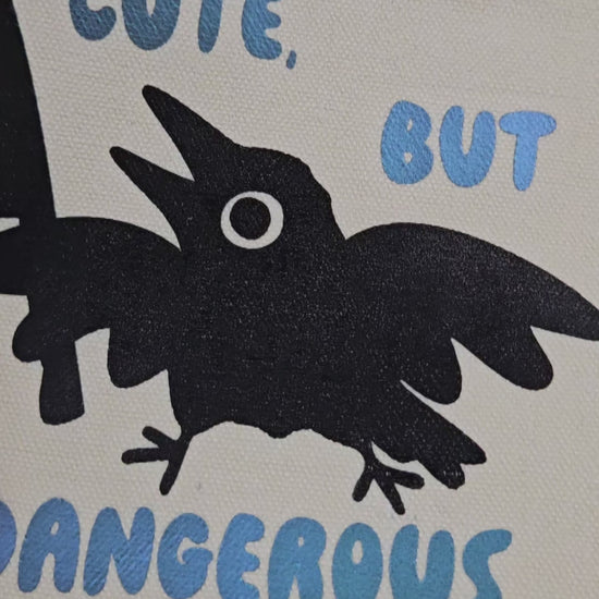 Video of a Canvas Pencil Bag with silhouette image of crow holding a knife and it says "cute, but dangerous" 