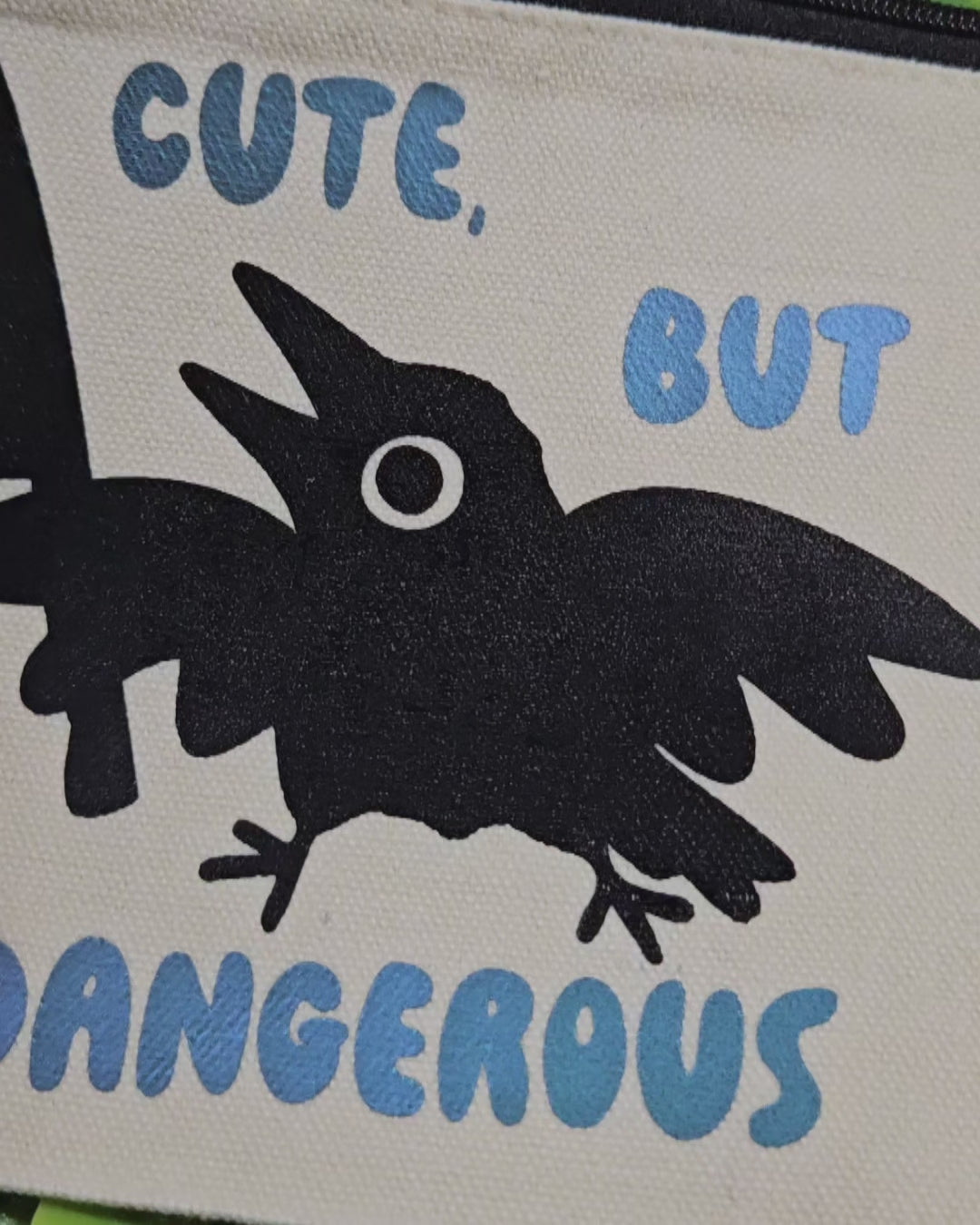 Video of a Canvas Pencil Bag with silhouette image of crow holding a knife and it says "cute, but dangerous" 